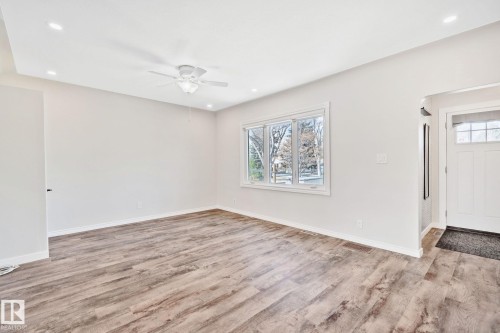 Spacious room featuring wood-finish flooring, white walls, and a ceiling fan with integrated lighting - 13635 108 Avenue, Edmonton, AB - Indoor Photo Showing Other Room