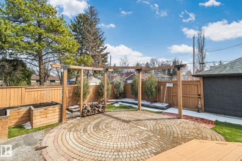 Expansive backyard featuring a circular paver patio, pergola structure, raised planter beds, and a wood privacy fence - 13635 108 Avenue, Edmonton, AB - Outdoor With Deck Patio Veranda