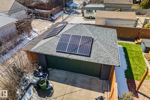 Detached garage featuring solar panels, a dark green garage door, and a shingled roof - 13635 108 Avenue, Edmonton, AB - Outdoor With Exterior