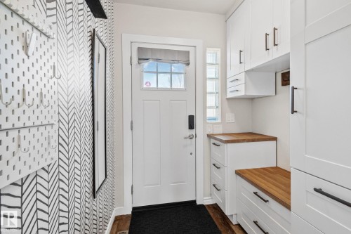 Entryway featuring a paneled door with glass inserts, patterned accent wall, wood-finish flooring, built-in white cabinetry, and wood countertops - 13635 108 Avenue, Edmonton, AB - Indoor Photo Showing Other Room