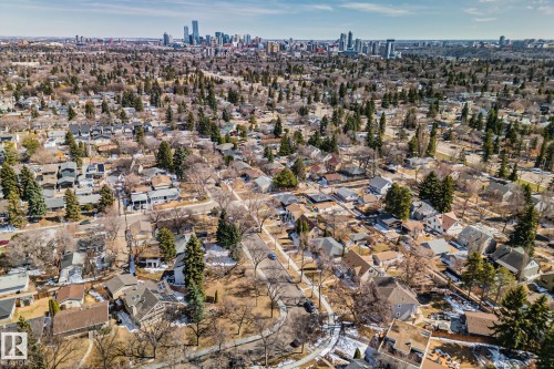 Extensive residential landscape featuring numerous single-family homes, mature trees, and a distant cityscape under a clear sky - 13635 108 Avenue, Edmonton, AB - Outdoor With View
