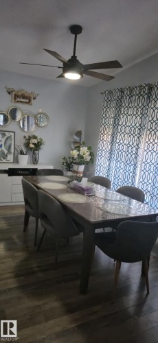 Dining area featuring hardwood style flooring, a ceiling fan with integrated lighting, and patterned curtains - 5420 40 Avenue, Wetaskiwin, AB - Indoor