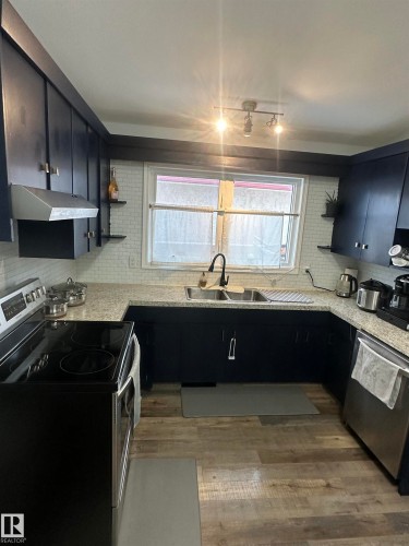 Kitchen featuring dark cabinetry, light-colored countertops, and a subway tile backsplash - 5420 40 Avenue, Wetaskiwin, AB - Indoor Photo Showing Kitchen With Double Sink