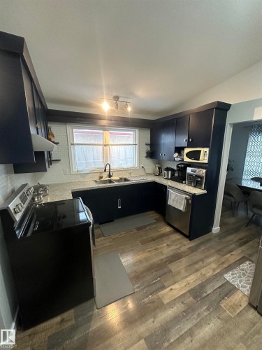 The kitchen features dark cabinetry with silver hardware, light-colored countertops, and a subway tile backsplash - 5420 40 Avenue, Wetaskiwin, AB - Indoor Photo Showing Kitchen
