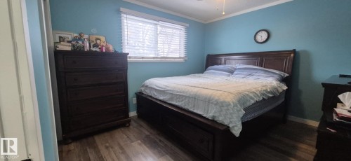 The room features wood-look flooring, a window with blinds, and light blue walls with white trim - 5420 40 Avenue, Wetaskiwin, AB - Indoor Photo Showing Bedroom