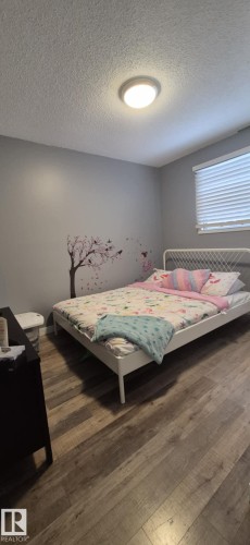 This room features wood-style flooring, a window with horizontal blinds, and a ceiling light fixture - 5420 40 Avenue, Wetaskiwin, AB - Indoor Photo Showing Bedroom