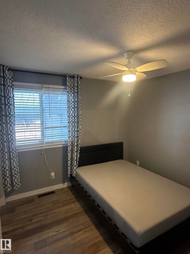 Bedroom featuring wood-style flooring, a window with blinds, and a ceiling fan with integrated lighting - 5420 40 Avenue, Wetaskiwin, AB - Indoor Photo Showing Bedroom