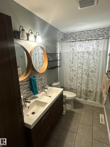 Bathroom featuring a dual vanity with rectangular sinks, modern faucets, and a dark wood cabinet - 5420 40 Avenue, Wetaskiwin, AB - Indoor Photo Showing Bathroom