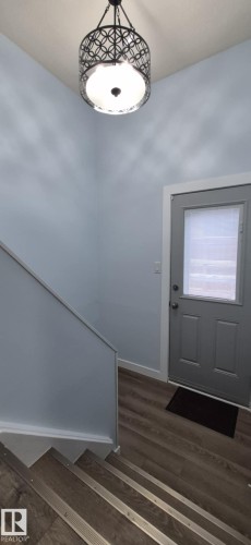 Entryway featuring a modern ceiling light fixture, light blue walls, and durable flooring on the stairs and landing - 5420 40 Avenue, Wetaskiwin, AB - Indoor Photo Showing Other Room