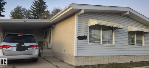 The property features light-colored siding and a covered carport with a paved driveway - 5420 40 Avenue, Wetaskiwin, AB - Outdoor With Exterior