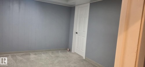 This room features soft gray carpeting, painted walls, and a white paneled door - 5420 40 Avenue, Wetaskiwin, AB - Indoor Photo Showing Other Room