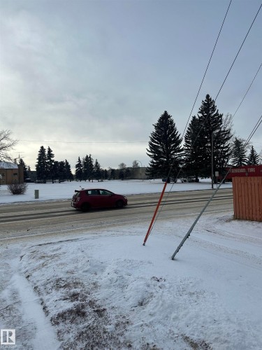 The property is located in a community featuring mature evergreen trees and a road with visible lanes - 5420 40 Avenue, Wetaskiwin, AB - Outdoor With View