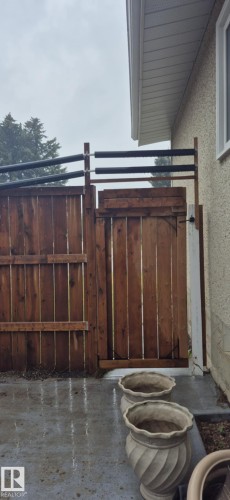 The property features a wooden fence and gate, a concrete patio area, and a light-colored exterior wall with a white window frame and eavestrough - 5420 40 Avenue, Wetaskiwin, AB - Outdoor