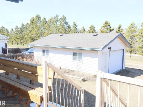 Detached garage featuring white siding, an overhead door, and a side access door - 5802 52 Avenue, Barrhead, AB - Outdoor With Exterior