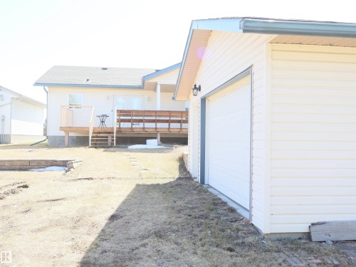 Detached garage with horizontal siding, a single garage door, and an exterior wall sconce - 5802 52 Avenue, Barrhead, AB - Outdoor