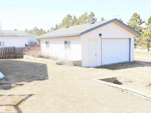 Detached garage featuring white siding, a white overhead door, and a separate pedestrian entry - 5802 52 Avenue, Barrhead, AB - Outdoor