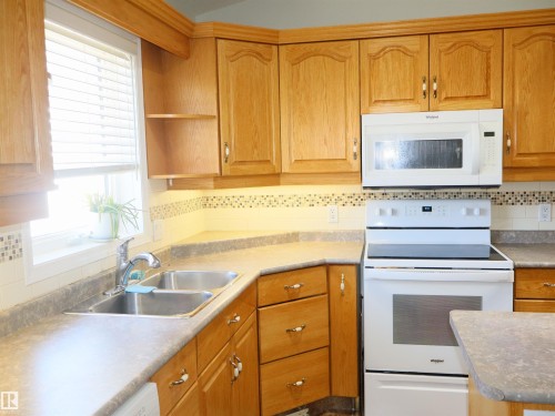Kitchen featuring wood-finish cabinetry, built-in microwave, and electric range - 5802 52 Avenue, Barrhead, AB - Indoor Photo Showing Kitchen With Double Sink