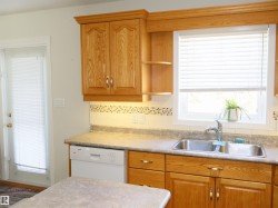 Kitchen featuring natural wood cabinetry with crown molding, double basin stainless steel sink, built-in dishwasher, and a window with blinds - 