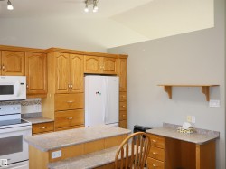 Kitchen featuring extensive wood cabinetry, white appliances, a peninsula with seating space, and a built-in desk area - 