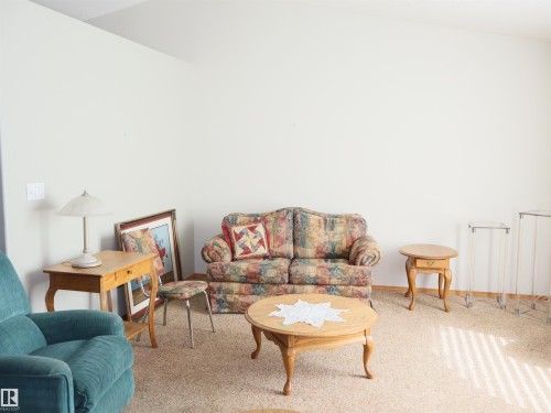Spacious room featuring vaulted ceilings and neutral carpeting - 5802 52 Avenue, Barrhead, AB - Indoor Photo Showing Living Room