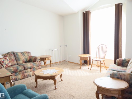 Carpeted interior space featuring white walls and a large window with brown drapes - 5802 52 Avenue, Barrhead, AB - Indoor Photo Showing Living Room