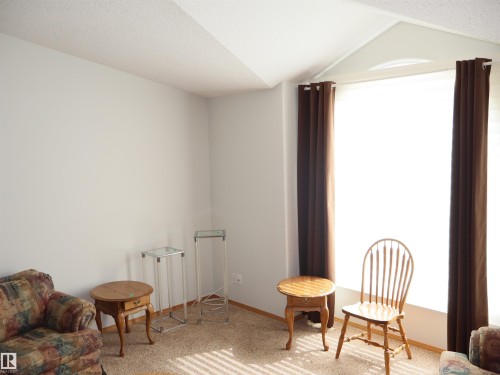 Bright living space with neutral wall tones and textured carpeting - 5802 52 Avenue, Barrhead, AB 