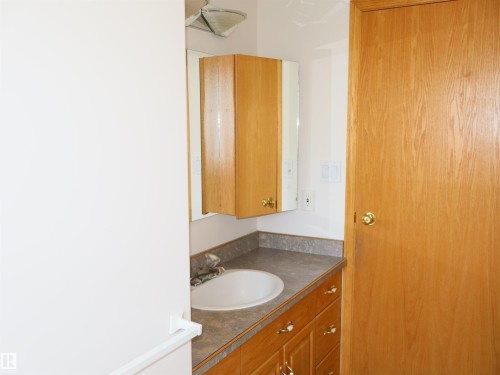 Vanity area featuring wood-finish cabinetry, a white oval sink, and a dark countertop - 5802 52 Avenue, Barrhead, AB - Indoor Photo Showing Bathroom