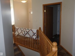 Natural wood banister and railing with a paneled door and light-toned walls - 
