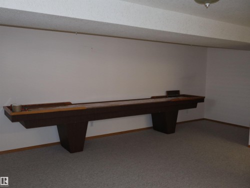 Spacious recreation room featuring a built-in shuffleboard, neutral carpeting, and white painted walls - 5802 52 Avenue, Barrhead, AB - Indoor Photo Showing Other Room