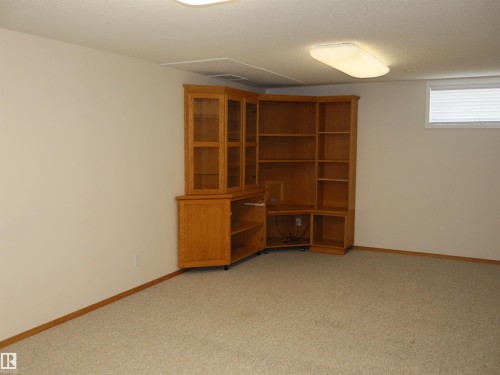 Built-in wood cabinetry with glass-fronted upper sections, open shelving, and a dedicated media console space - 5802 52 Avenue, Barrhead, AB - Indoor Photo Showing Other Room