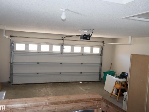 Attached garage space featuring a paneled overhead door with upper window inserts, concrete flooring, and an automatic garage door opener - 5802 52 Avenue, Barrhead, AB - Indoor Photo Showing Garage