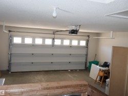 Attached garage space featuring a paneled overhead door with upper window inserts, concrete flooring, and an automatic garage door opener - 