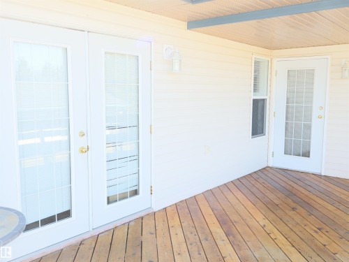 Covered wood deck with dual French doors, a single glass-paneled door, and beige siding - 5802 52 Avenue, Barrhead, AB -  Photo Showing Other Room