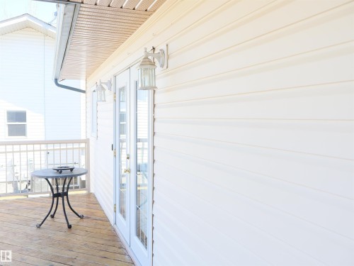Outdoor deck featuring wood-finish flooring and white metal railing - 5802 52 Avenue, Barrhead, AB - Outdoor