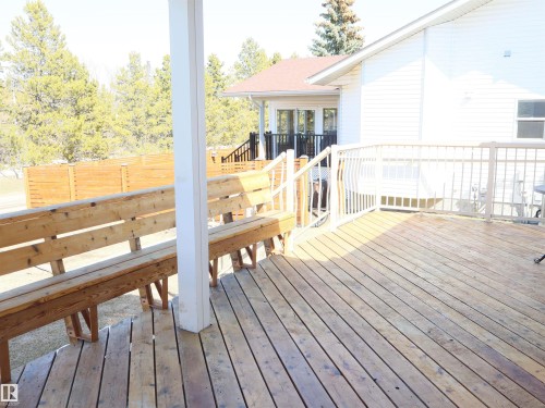 Expansive wood-finish deck featuring integrated bench seating, white railing, and a privacy fence - 5802 52 Avenue, Barrhead, AB - Outdoor With Deck Patio Veranda With Exterior