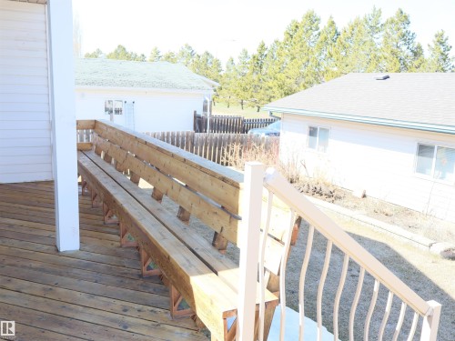 Spacious wood deck with built-in bench seating and white railing - 5802 52 Avenue, Barrhead, AB - Outdoor With Exterior