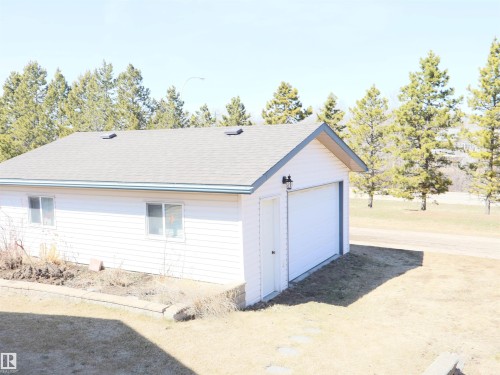 Detached garage structure featuring white siding, a gray shingle roof, and a white garage door - 5802 52 Avenue, Barrhead, AB - Outdoor With Exterior