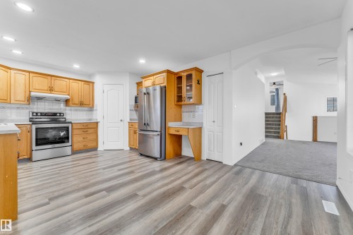 Contemporary kitchen featuring stainless steel appliances, light wood-finish cabinetry, light countertops, a tile backsplash, and wood-finish flooring - 4103 37A Avenue, Edmonton, AB - Indoor Photo Showing Kitchen
