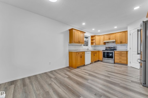 Kitchen featuring wood cabinetry, stainless steel range, light-toned countertops, and a patterned tile backsplash - 4103 37A Avenue, Edmonton, AB - Indoor Photo Showing Kitchen