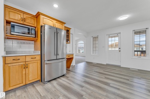 Kitchen area featuring new wood-finish flooring, light wood cabinetry, stainless steel refrigerator, and a built-in microwave - 4103 37A Avenue, Edmonton, AB - Indoor Photo Showing Kitchen