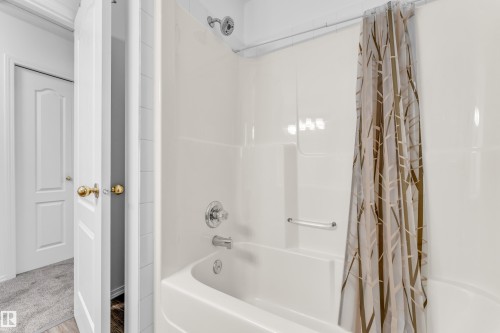 White bathtub with a chrome showerhead and faucet - 4103 37A Avenue, Edmonton, AB - Indoor Photo Showing Bathroom