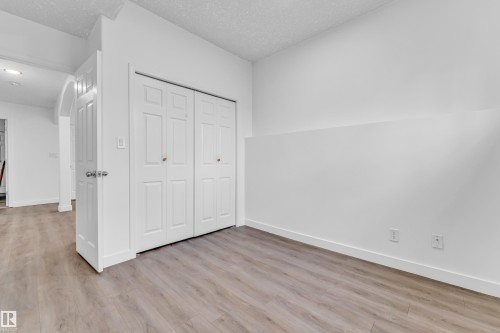 Room featuring light wood-finish flooring, white walls, and a built-in bifold closet with paneled doors - 4103 37A Avenue, Edmonton, AB - Indoor Photo Showing Other Room