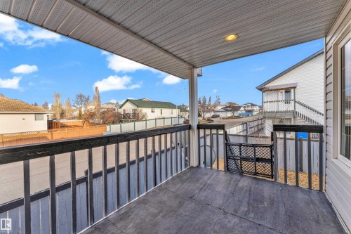 Covered outdoor deck with a dark-toned floor, dark wooden railings, and soffit lighting - 4103 37A Avenue, Edmonton, AB - Outdoor With Deck Patio Veranda With Exterior
