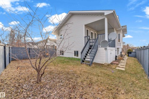 Rear exterior showcasing light-toned siding, a covered deck with stairs, a compact lawn area, and a dark-toned privacy fence - 4103 37A Avenue, Edmonton, AB - Outdoor