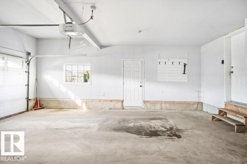 Spacious garage featuring a concrete floor, overhead garage door, and a paneled window for natural light - 4103 37A Avenue, Edmonton, AB - Indoor Photo Showing Garage