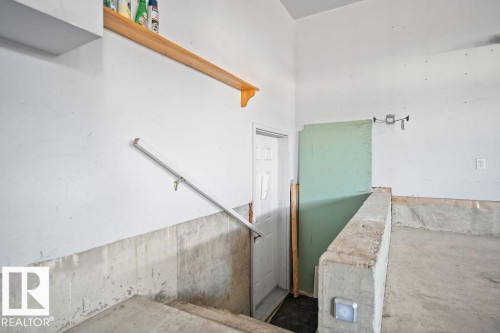 Concrete steps with a white metal handrail, leading to a white paneled door - 4103 37A Avenue, Edmonton, AB - Indoor Photo Showing Other Room