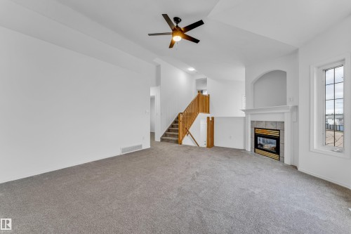 Spacious living area featuring a built-in fireplace with a tiled surround and white mantel, a ceiling fan, and carpet flooring - 4103 37A Avenue, Edmonton, AB - Indoor With Fireplace