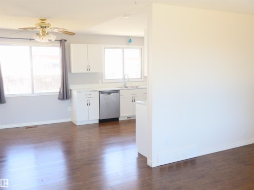 Kitchen area featuring white cabinetry, light countertops, and a stainless steel dishwasher - 4934 49 Avenue, Barrhead, AB - Indoor Photo Showing Other Room