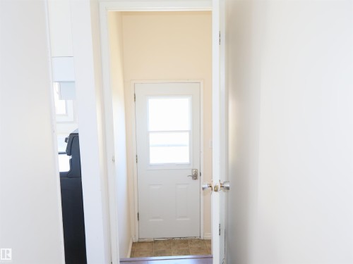 White paneled door with upper window, complemented by light-colored walls and tiled flooring - 4934 49 Avenue, Barrhead, AB - Indoor Photo Showing Other Room