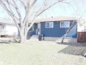 Blue siding exterior with multiple windows, concrete foundation, and a partial wood fence - 4934 49 Avenue, Barrhead, AB  - Outdoor 